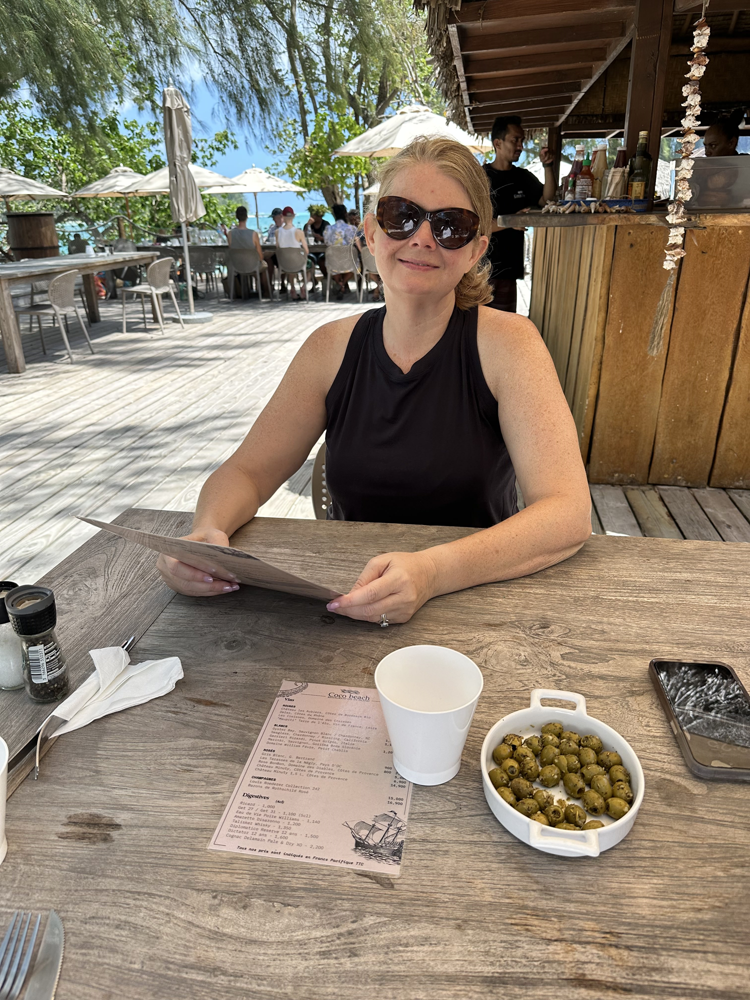 Personal Travel Planner Brandie sitting at a picnic table on the white sand motu at Coco Beach in Moorea, French Polynesia