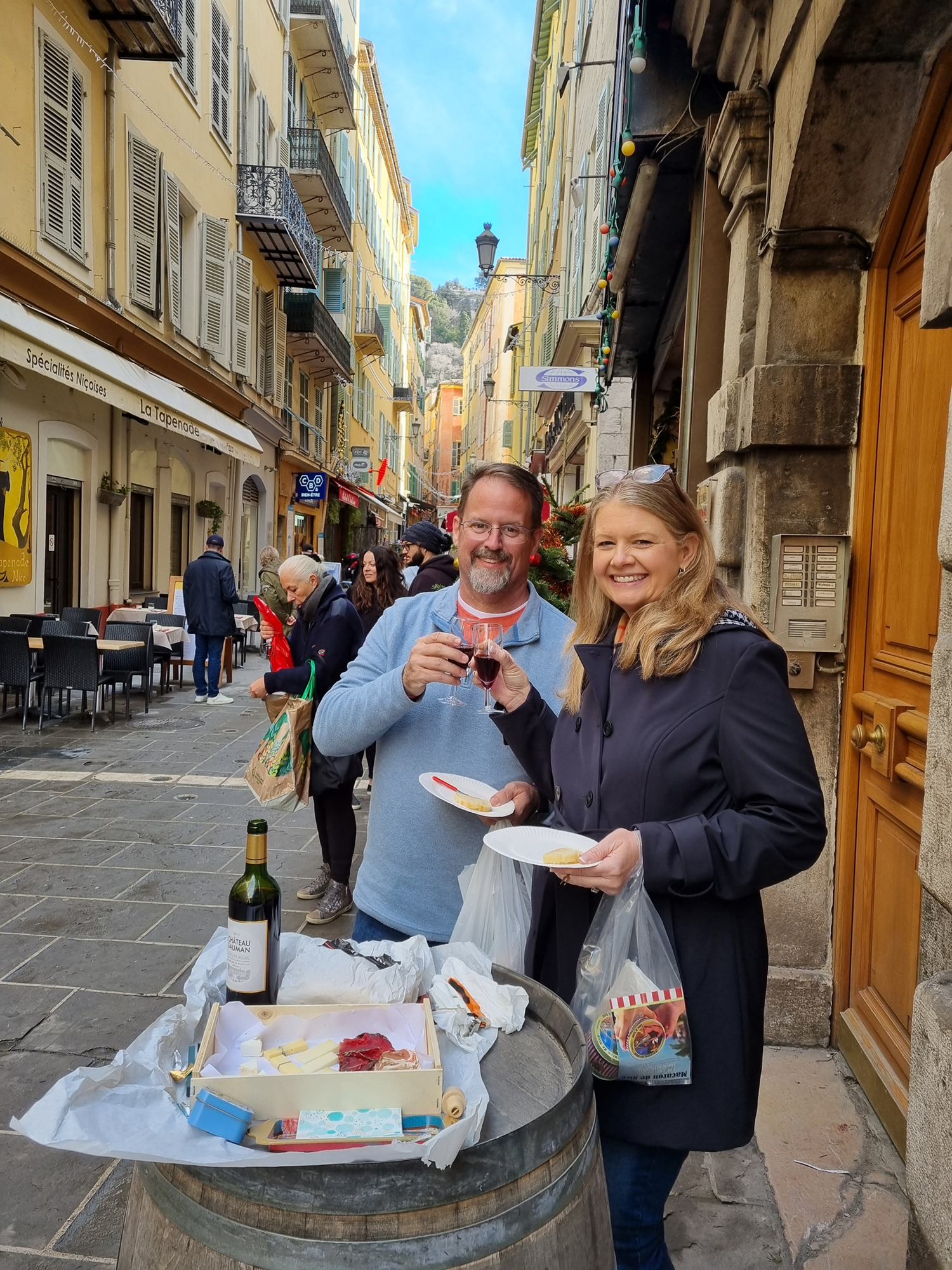 Brandie and John on a food tour in Nice, France. Enjoying wine and artisan cheese in an alley in front of a wine shop