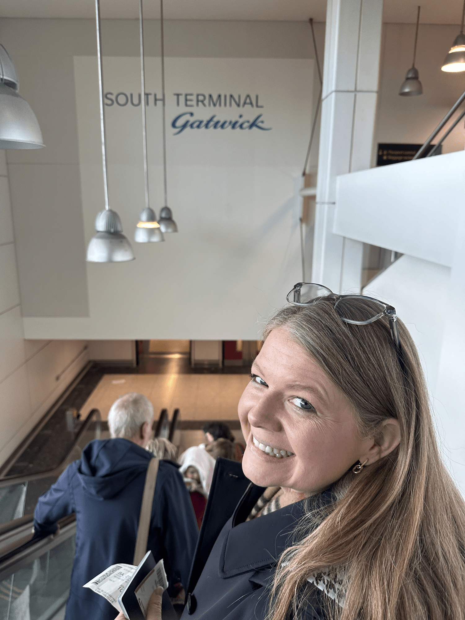Personal Travel Planner Brandie on the escalator arriving at London Gatwick airport, heading for the train into central London