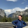Happy client Haley P standing in front of a majestic mountain range, pleased with the local knowledge our itineraries include